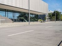 a woman is walking by the modern building on the street with skateboards in hand