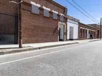 an empty street in a downtown area that includes brick buildings and several stairs in the corner