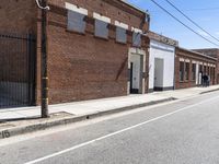 an empty street in a downtown area that includes brick buildings and several stairs in the corner