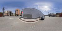 the picture is taken in a fisheye lens of a building and some cars and buildings