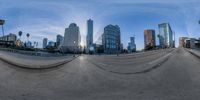 a large metal fish eye lens view shows an intersection in los angeles, ca, with many other city buildings