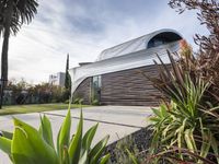 the house is located in the middle of the street and has lots of plants and trees