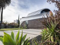 the house is located in the middle of the street and has lots of plants and trees