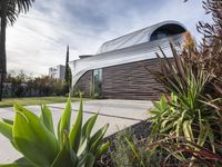 the house is located in the middle of the street and has lots of plants and trees