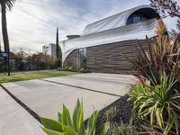 the house is located in the middle of the street and has lots of plants and trees