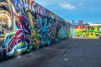 street art on the walls in a parking lot with tall buildings in the background and blue skies above