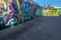 street art on the walls in a parking lot with tall buildings in the background and blue skies above