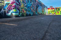 street art on the walls in a parking lot with tall buildings in the background and blue skies above