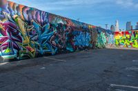 street art on the walls in a parking lot with tall buildings in the background and blue skies above