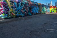 street art on the walls in a parking lot with tall buildings in the background and blue skies above