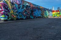 street art on the walls in a parking lot with tall buildings in the background and blue skies above