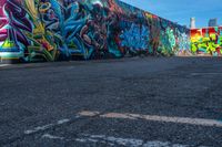 street art on the walls in a parking lot with tall buildings in the background and blue skies above