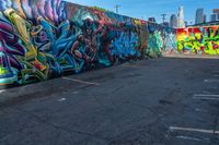 street art on the walls in a parking lot with tall buildings in the background and blue skies above