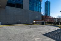 a clock is standing next to a parking garage and a building with windows on it