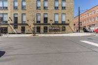 there is a large building on the corner of a street and a man riding a bike behind it