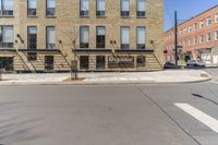 there is a large building on the corner of a street and a man riding a bike behind it