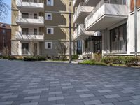 a man is walking in the yard next to a building with windows and balconys