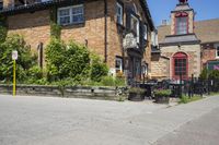 a brick building sitting next to a sidewalk with lots of chairs and umbrellas hanging from it and a car parked outside