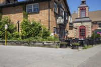 a brick building sitting next to a sidewalk with lots of chairs and umbrellas hanging from it and a car parked outside