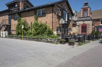 a brick building sitting next to a sidewalk with lots of chairs and umbrellas hanging from it and a car parked outside