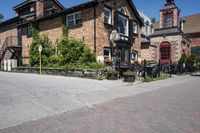 a brick building sitting next to a sidewalk with lots of chairs and umbrellas hanging from it and a car parked outside