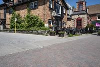 a brick building sitting next to a sidewalk with lots of chairs and umbrellas hanging from it and a car parked outside