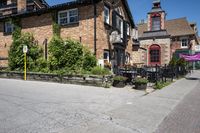 a brick building sitting next to a sidewalk with lots of chairs and umbrellas hanging from it and a car parked outside