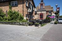 a brick building sitting next to a sidewalk with lots of chairs and umbrellas hanging from it and a car parked outside