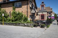 a brick building sitting next to a sidewalk with lots of chairs and umbrellas hanging from it and a car parked outside
