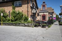 a brick building sitting next to a sidewalk with lots of chairs and umbrellas hanging from it and a car parked outside