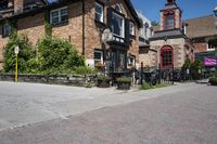 a brick building sitting next to a sidewalk with lots of chairs and umbrellas hanging from it and a car parked outside