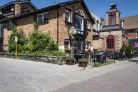 a brick building sitting next to a sidewalk with lots of chairs and umbrellas hanging from it and a car parked outside