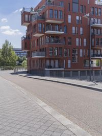 a person on a bike riding near a building with balconys on the side of the road