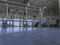 some people in an indoor building with blue lines on the floor and yellow poles at the entrance