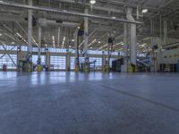 some people in an indoor building with blue lines on the floor and yellow poles at the entrance