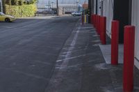 a car parked in the driveway by some red poles on a sunny day with cars in the background