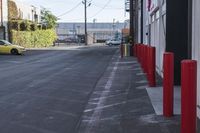 a car parked in the driveway by some red poles on a sunny day with cars in the background