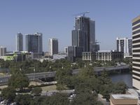 a city filled with tall buildings next to a highway under a blue sky overhead the street