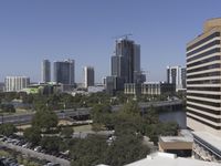 a city filled with tall buildings next to a highway under a blue sky overhead the street