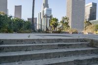 there are concrete steps on the sidewalk with trees in the background and city buildings on both sides