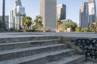 there are concrete steps on the sidewalk with trees in the background and city buildings on both sides