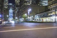 street lights lit up against the city skyline at night, near an empty intersection with traffic