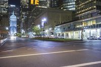 street lights lit up against the city skyline at night, near an empty intersection with traffic