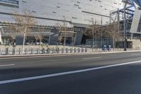 an empty highway is seen through a metal fence outside a building with a glass roof