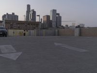 the city skyline is in the distance behind the parking lot, with yellow markings painted on the floor