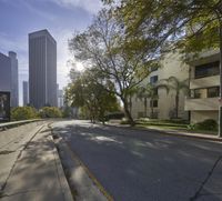 an empty street in front of a bunch of tall buildings on a sunny day,