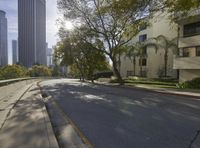 an empty street in front of a bunch of tall buildings on a sunny day,