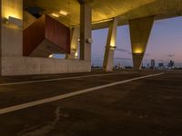 an empty parking lot surrounded by some concrete columns and lights on the sides of it