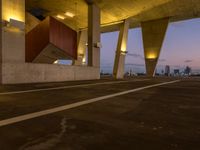 an empty parking lot surrounded by some concrete columns and lights on the sides of it