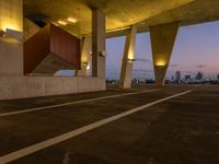 an empty parking lot surrounded by some concrete columns and lights on the sides of it